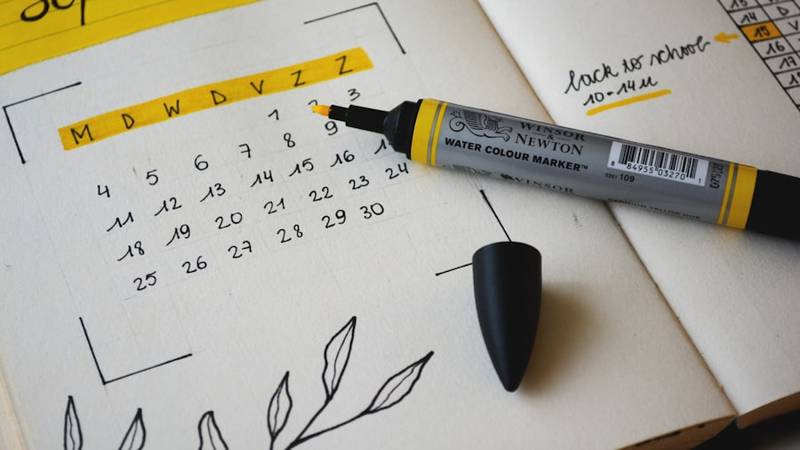 カレンダーとパソコンを前にブログ記事投稿スケジュールを管理している個人事業主の様子